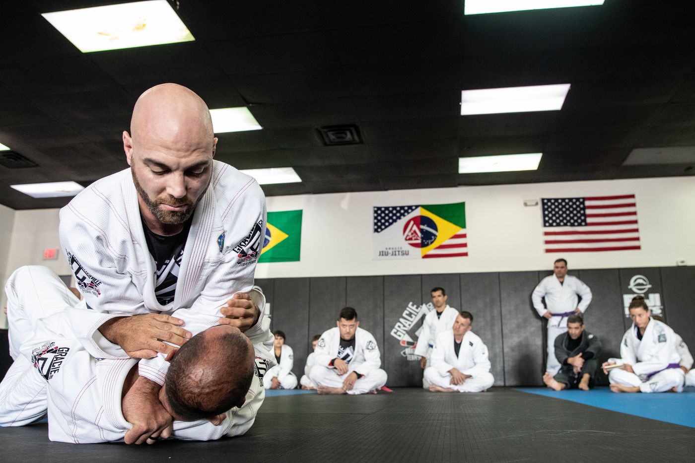 Brent Lillard, in a white gi, showing a technique on the mat
