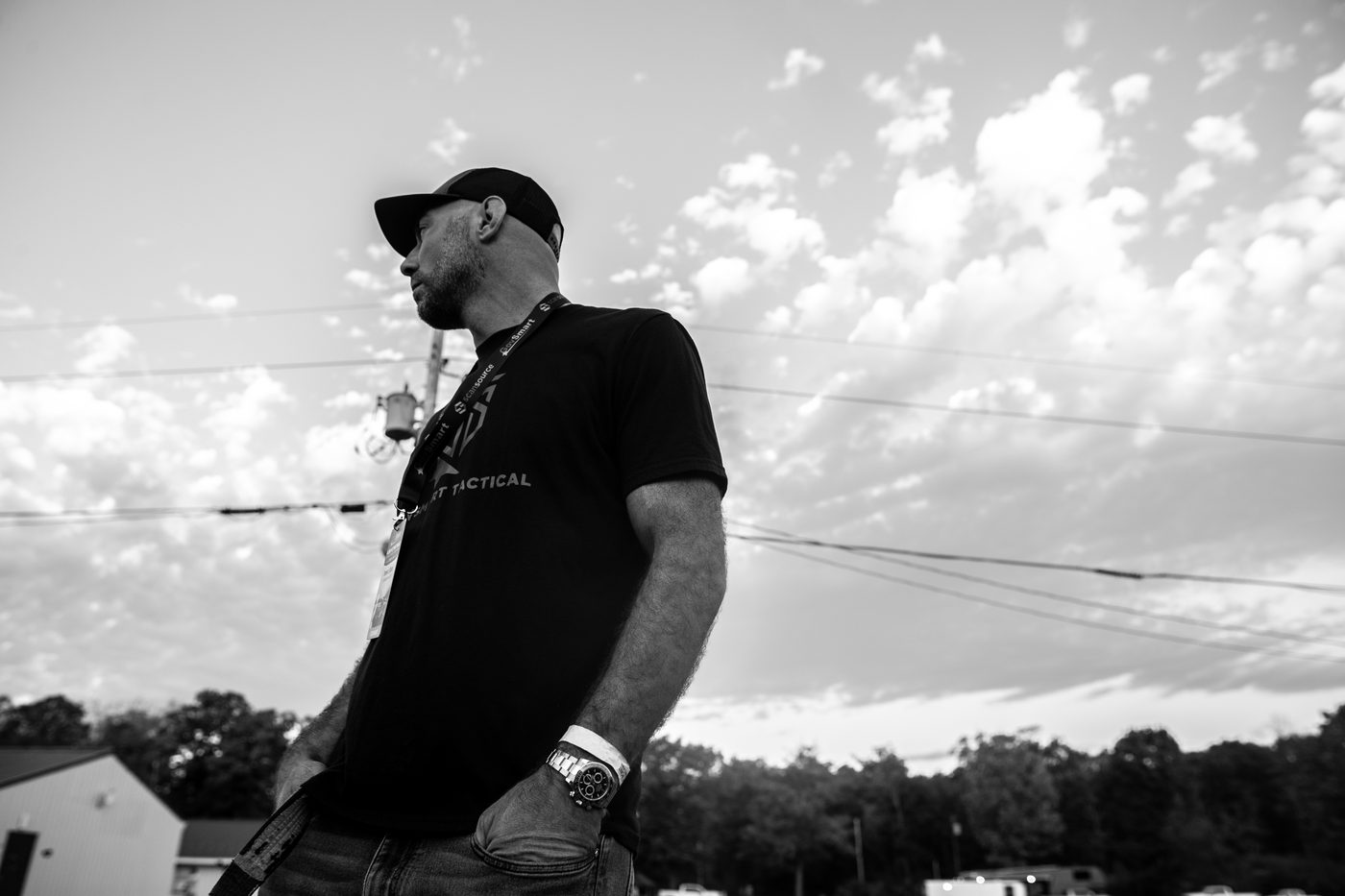 Black and white photo of Brent Lillard in a cap and lanyard at a track event