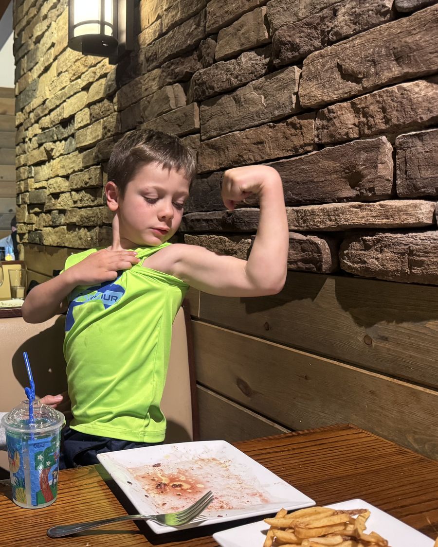 One of the Lillard boys flexing his arm at a restaurant table
